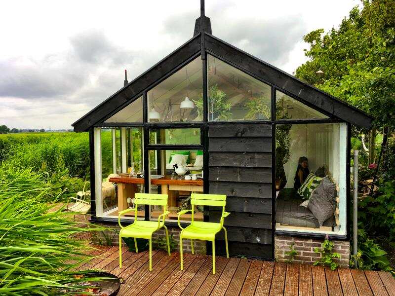 Tiny house met groene stoelen voor het huisje